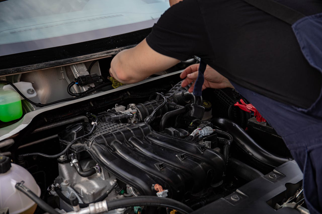Close-up of a mechanic working on car engine. Ideal for automotive maintenance and repair themes.
